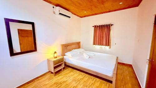 a bedroom with a white bed and a mirror at Abbi Holidays - Keerimalai Cultural Villa in Kankesanturai
