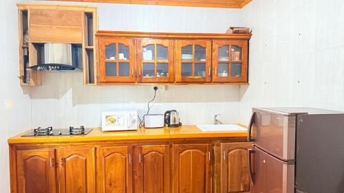 a kitchen with wooden cabinets and a refrigerator at Abbi Holidays - Keerimalai Cultural Villa in Kankesanturai