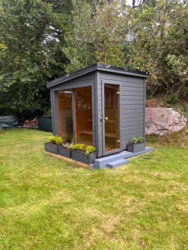 a small grey shed with flowers in a yard at Caragh Lake House - Lakefront Escape and Sauna in Killorglin