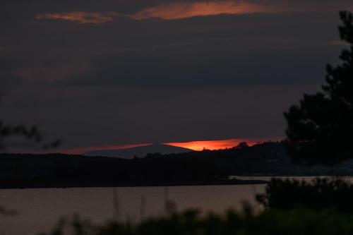 a sunset over a lake with a mountain in the background at Caragh Lake House - Lakefront Escape and Sauna in Killorglin