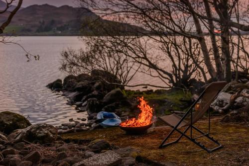 a fire in a bowl next to a lake at Caragh Lake House - Lakefront Escape and Sauna in Killorglin