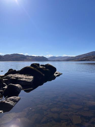a large body of water with rocks in the water at Caragh Lake House - Lakefront Escape and Sauna in Killorglin