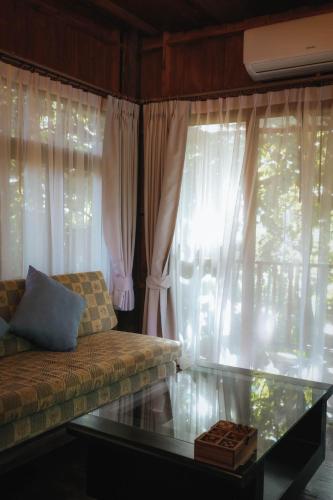 a living room with a couch and a glass table at บ้านสวนแก้วคำแพง Baan Suan Kaew Khampaeng in Udon Thani