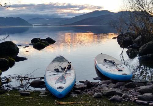 two kayaks sitting on the shore of a lake at Caragh Lake House - Lakefront Escape and Sauna in Killorglin