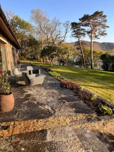a stone patio with two chairs and a couch at Caragh Lake House - Lakefront Escape and Sauna in Killorglin