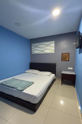 a bedroom with a bed and a blue wall at Hotel 3Winz, Chow Kit Hospital Kuala Lumpur in Kuala Lumpur