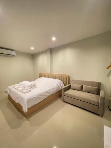 a bedroom with a bed and a couch and a chair at HOMETELhdy in Hat Yai