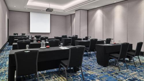 a conference room with tables and chairs and a screen at Holiday Inn Singapore Atrium by IHG in Singapore
