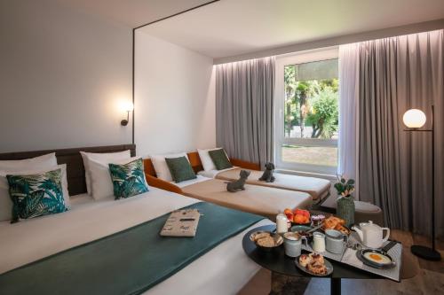 a room with a bed and a table with food on it at Novotel Nice Aéroport Cap 3000 in Saint-Laurent-du-Var