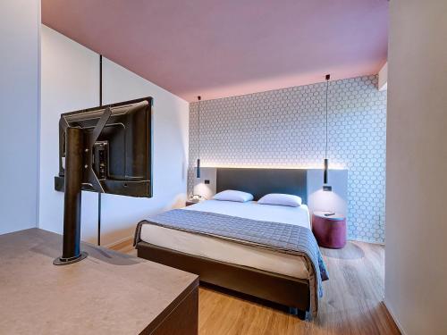 a bedroom with a bed and a flat screen tv at Hotel Excelsior in Cervia