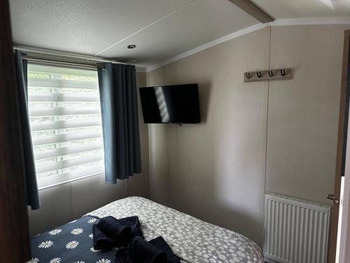 a bedroom with a bed and a television on the wall at Tranquil Caravan Retreat by the Seaside PortSeton in Prestonpans