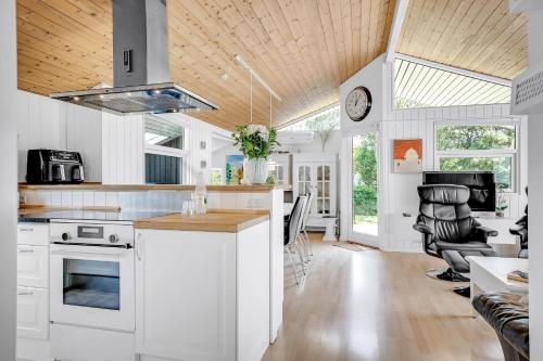 a kitchen with white cabinets and a wooden ceiling at Lovely Spa House In Scenic Surroundings in Thyholm
