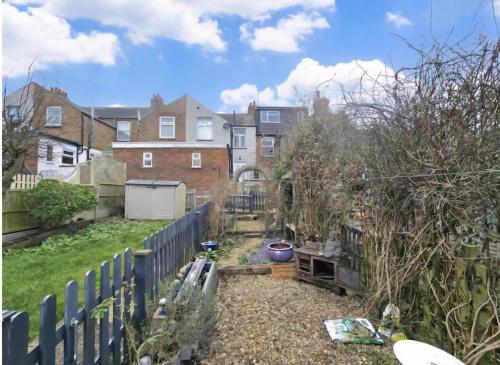 a backyard with a fence and a house at Cosy Village Retreat in Long Buckby