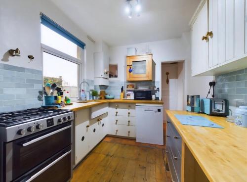 a kitchen with white cabinets and a stove top oven at Cosy Village Retreat in Long Buckby