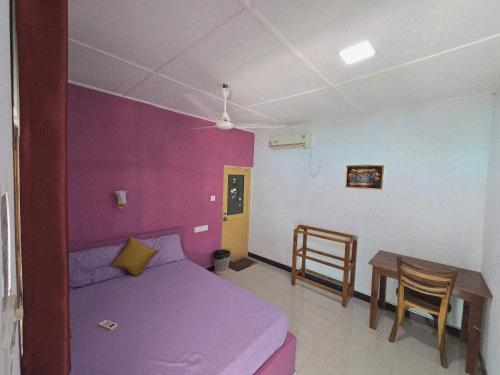 a bedroom with a purple bed and a table at Hotel Angel Inn Beach in Trincomalee