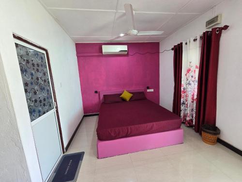 a purple bed in a room with a pink wall at Hotel Angel Inn Beach in Trincomalee