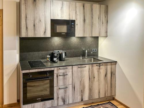 a kitchen with wooden cabinets and a sink and a microwave at Madlhof in Himmelreich