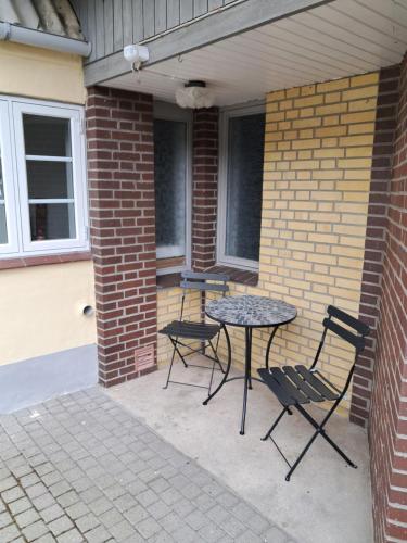 a patio with a table and chairs and a brick wall at Naturskønt nær Ribe Vikingecenter, se og oplev den gamle by Ribe in Ribe