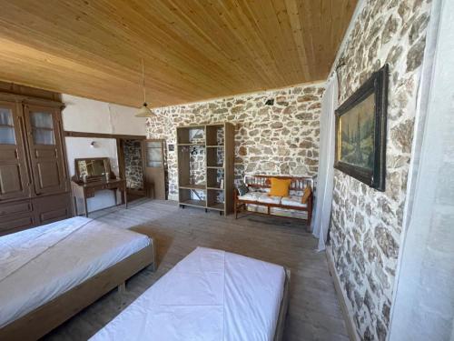 een slaapkamer met twee bedden en een stenen muur bij Myra in Himare
