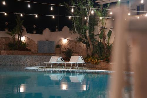 two lounge chairs next to a swimming pool at night at Hotel Club Perla in Casalabate