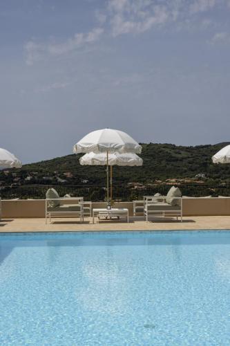 une piscine avec parasols et chaises à côté d'une piscinelictsangering dans l'établissement Résidence Omigna, à Cargèse