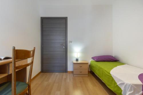 a bedroom with a bed and a desk and a door at Dolomiapartments - Appartamento CENTRALE in Predazzo