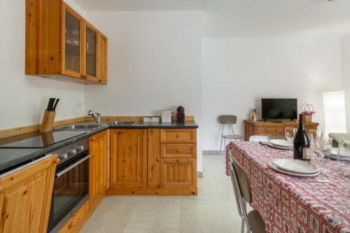 a kitchen with wooden cabinets and a table with a tablecloth at Dolomiapartments - Appartamento CENTRALE in Predazzo