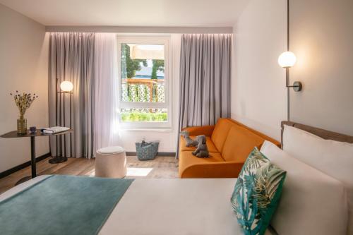 a bedroom with a bed and a couch and a window at Novotel Nice Aéroport Cap 3000 in Saint-Laurent-du-Var