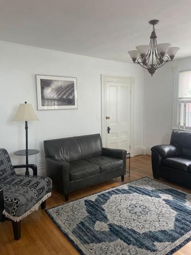 a living room with a leather couch and a chair at Beautiful West End Apartment in Portland