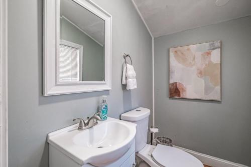 Un baño con lavabo, inodoro y espejo. en State of Charm - Historic West End Haven, en Portland