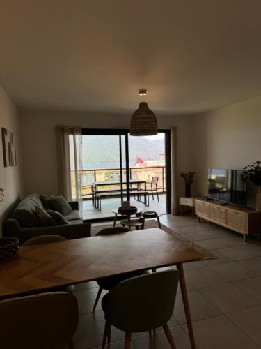 a living room with a table and a view of the ocean at Appart tout équipé et vue sur la mer in Propriano