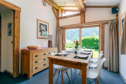 une salle à manger avec une table en bois et des chaises blanches dans l'établissement Chalet Martinique - Chamonix All Year, à Chamonix-Mont-Blanc