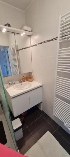 a white bathroom with a sink and a mirror at Résidence jersey in Koksijde