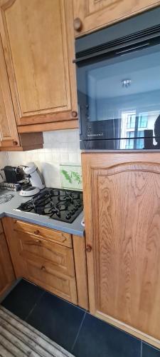 a kitchen with a stove and wooden cabinets at Résidence jersey in Koksijde