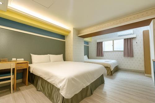a hotel room with two beds and a desk at Elizabeth Hotel in Taichung