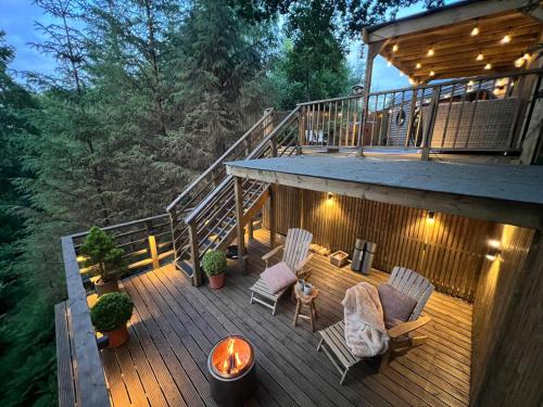 a deck with two chairs and a table on it at The Pines Treehouse at Treetops Hideouts in Richmond