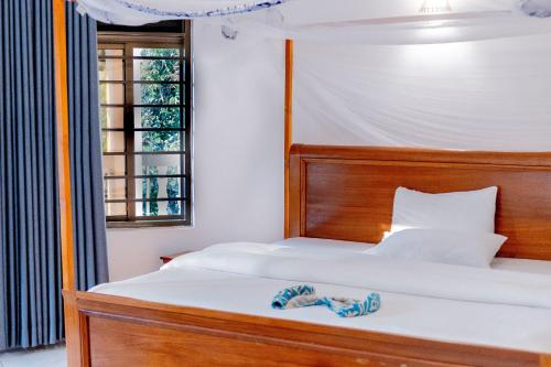 a bedroom with a bed with a wooden headboard and a window at Nature Kigali in Kigali