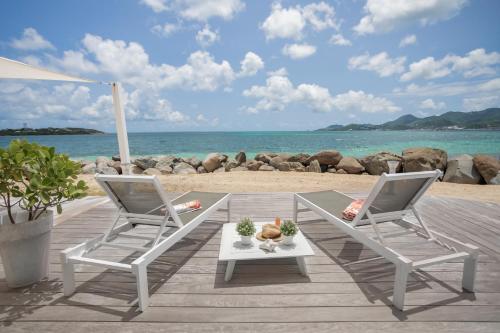 two chairs and a table on a dock with the beach at Sweet Home sur la plage in Marigot