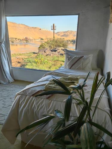 a bedroom with a bed and a large window at Nala Narty Boutique Hotel & Farm in Aswan