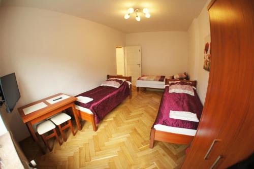 ポズナンにあるApartament Poznań Jeżyceのベッド2台とテーブルが備わる小さな客室です。