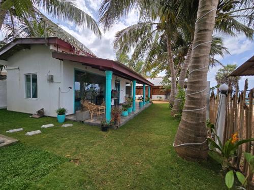 a house with a palm tree in the yard at Hotel Angel Inn Beach in Trincomalee