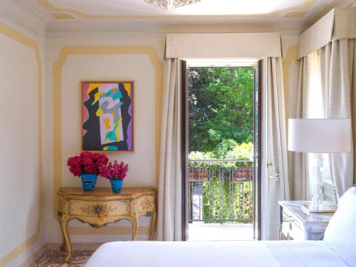 a bedroom with a bed and a window and a table with flowers at Hotel Cipriani, A Belmond Hotel, Venice in Venice