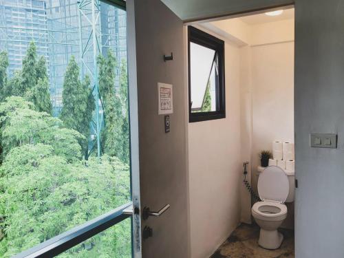 a bathroom with a toilet and a large window at HOLY SHEET Hostel in Bangkok