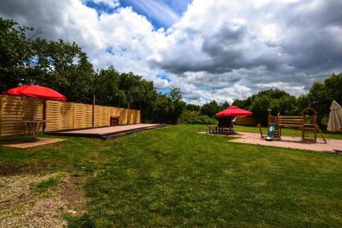 a park with two picnic tables and two red umbrellas at Gîte Oncle Yerry Ostheim in Ostheim
