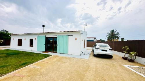 a white house with a car parked in a driveway at Villa Salinas Beach Home Natural Park in La Manga del Mar Menor
