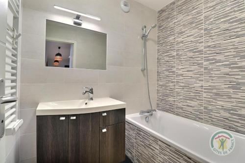 a bathroom with a sink and a tub and a mirror at Les ormelles in Montreuil-sur-Ille