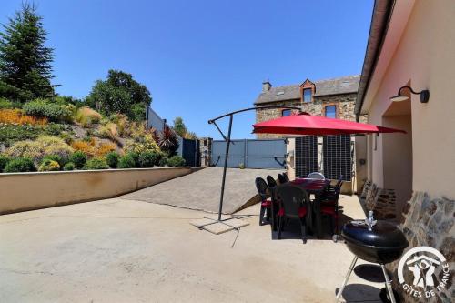 a patio with a table and chairs and an umbrella at Les ormelles in Montreuil-sur-Ille