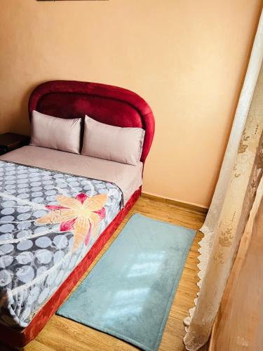 a bed with a red headboard and a blue rug at Hagounia hotel in Tan-Tan