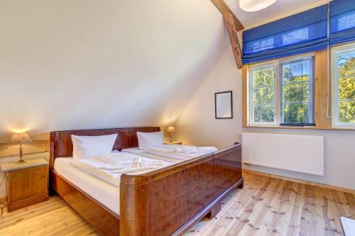 a bedroom with a wooden bed and windows at Katen am Schwanenteich in Lassan