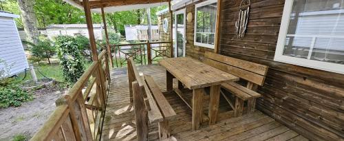 un banc en bois installé sur la terrasse couverte d'une maison dans l'établissement Mobil home accueillant à Aureilhan avec piscine partagée, 34 m², à Aureilhan